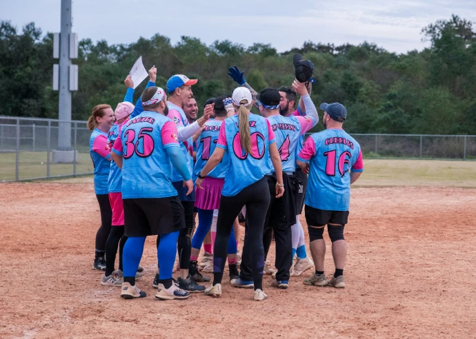 A group of softball players standing on top of a field
